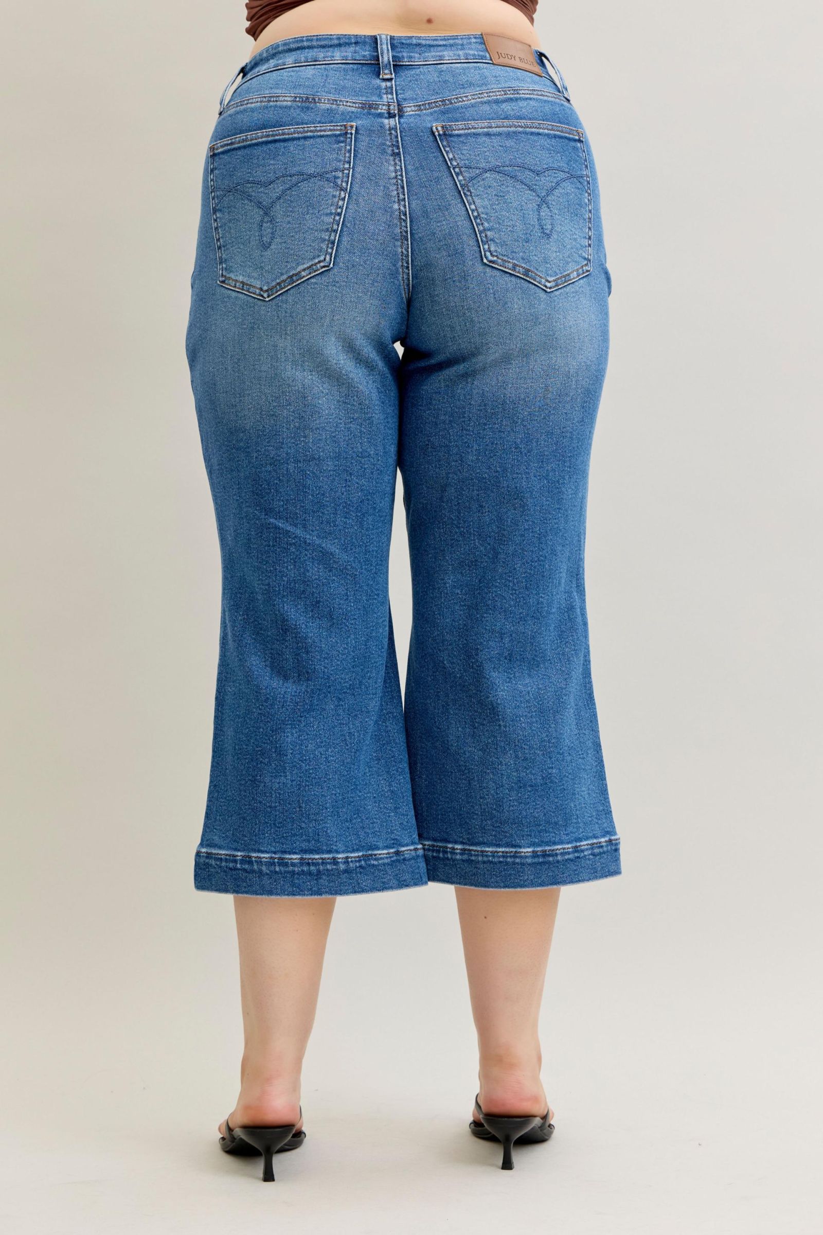 Judy Blue Capri Jeans in light blue with frayed hems, vintage pockets, and logo tag on waistband. Available in sizes 24–32.