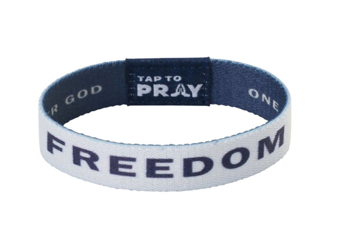 White elastic Tap To Pray™ Freedom wristband with navy blue “FREEDOM” print and interior “TAP TO PRAY” label with prayer hands icon.