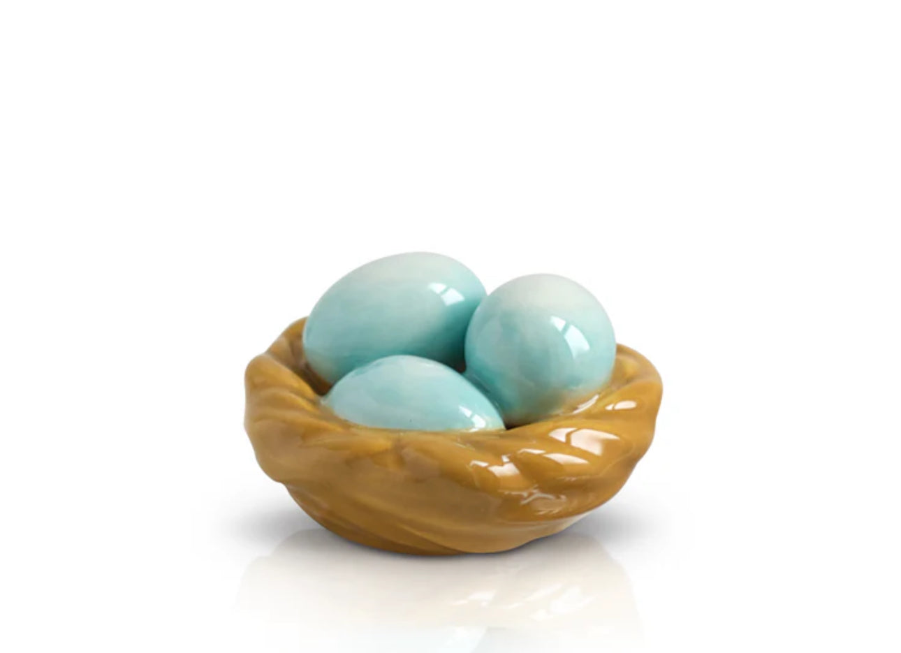 Mini ceramic sculpture of a bird's nest with three light blue eggs. Warm brown woven nest on a plain white base. Polished, glossy finish. Available size: Standard mini.
