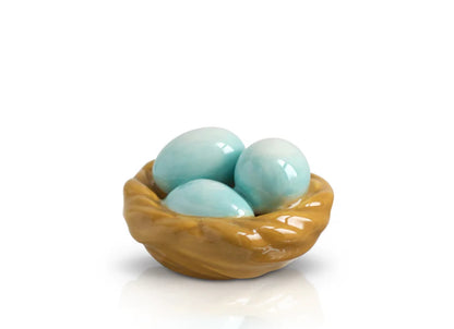 Mini ceramic sculpture of a bird's nest with three light blue eggs. Warm brown woven nest on a plain white base. Polished, glossy finish. Available size: Standard mini.
