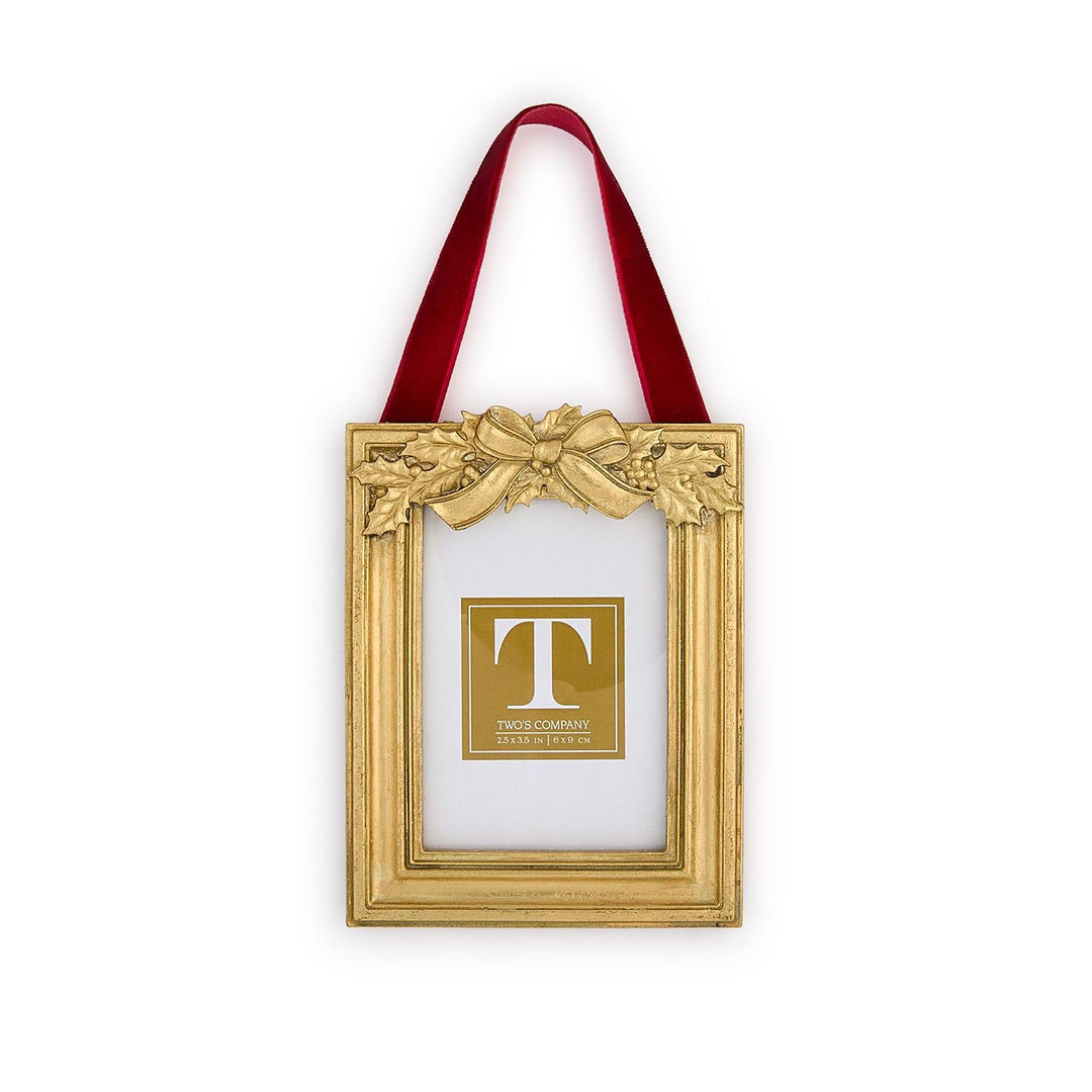Gold rectangular Holly Leaves Ornament Photo Frame with holly and ribbon motif, hanging from a red velvet ribbon.
