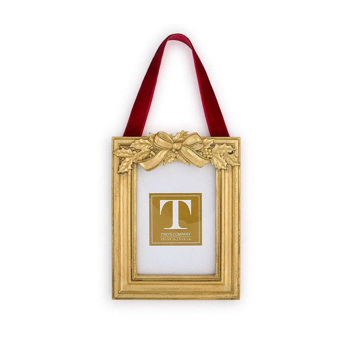 Gold rectangular Holly Leaves Ornament Photo Frame with holly and ribbon motif, hanging from a red velvet ribbon.