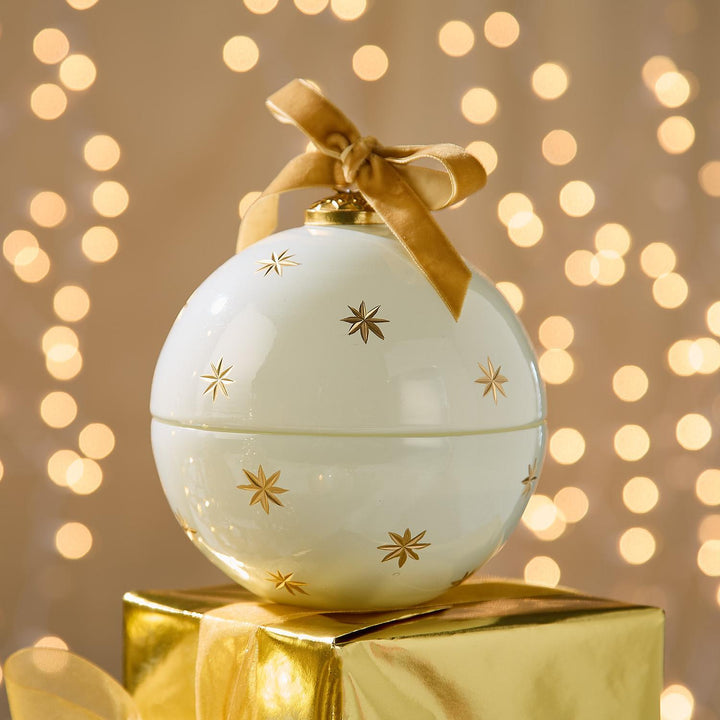 Sparkling Rose Ornament Candle: a white spherical candle with gold star accents and a gold ribbon bow.