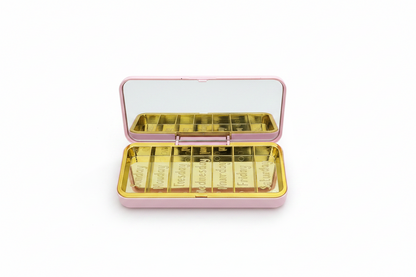 Pill Organizer With Mirror, pink exterior, seven gold compartments labeled for each day. Sizes available.
