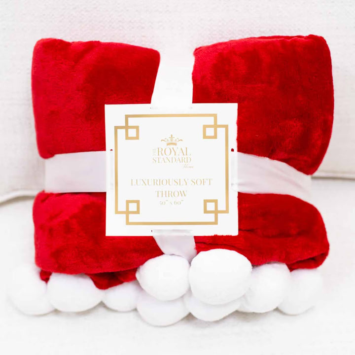 Santa Pom Pom Throw Blanket in red with white pom-pom trim, 50 by 60 inches.