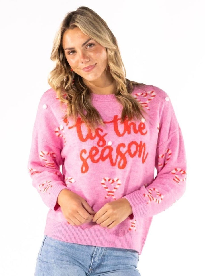 ‘Tis The Season Sweater: fuzzy pink Christmas sweater with red text and candy canes, available in sizes XS–XL.