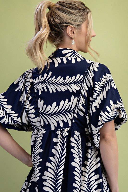 Navy blue midi dress with cream leaf print, short puff sleeves, and gathered back yoke. Available in multiple sizes.