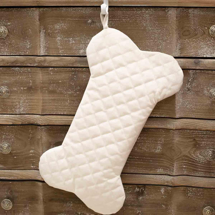 Cream-colored, diamond-quilted dog bone stocking with a hanging loop.