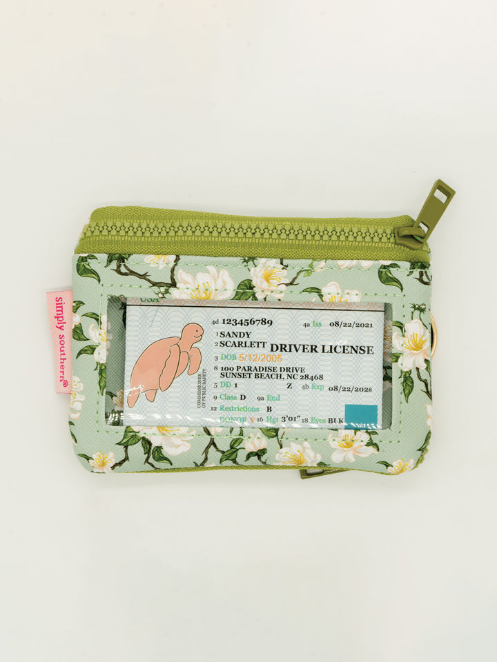 Small green floral ID wallet with zip pockets and clear window; displays mock license. Available in one compact size.