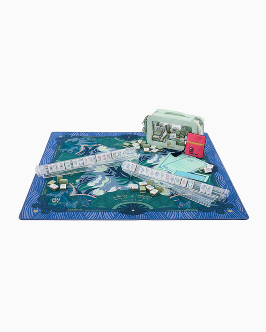 Mahjong Jade Mat in Tube features a blue and green board, play money, cards, game pieces, a mint green storage bag, and a pink card pouch. Available in multiple sizes.