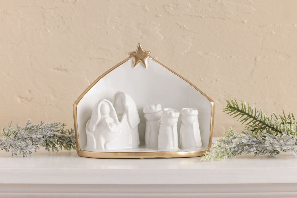 White ceramic Nativity scene with gold trim and a star at the peak.