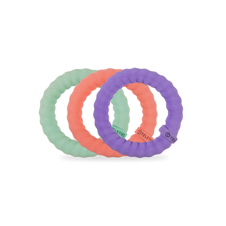 Three Teleties nylon hair ties in pastel green, coral, and purple. Available in small, medium, and large sizes.