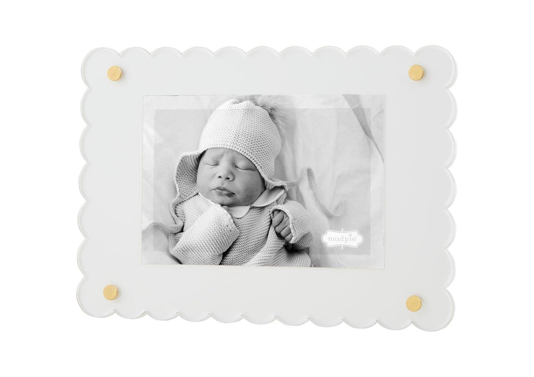 A black and white photo of a newborn baby wearing a knitted hat and wrapped in a soft blanket, displayed in a Scalloped Acrylic Frame with gold accents.