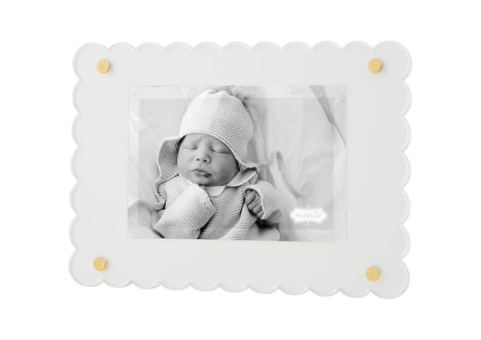 A black and white photo of a newborn baby wearing a knitted hat and wrapped in a soft blanket, displayed in a Scalloped Acrylic Frame with gold accents.
