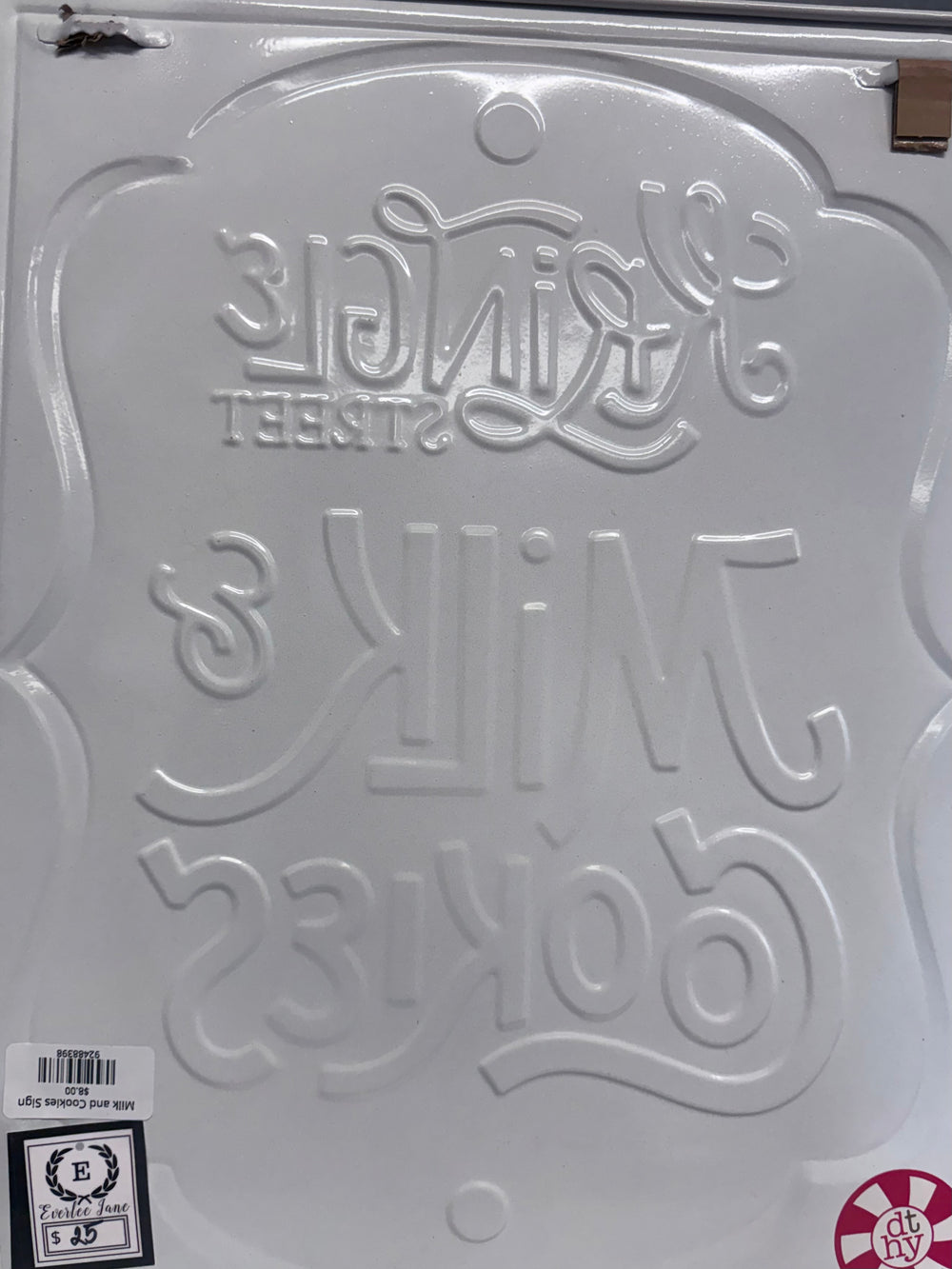 Embossed white metal Milk and Cookies sign with script lettering.