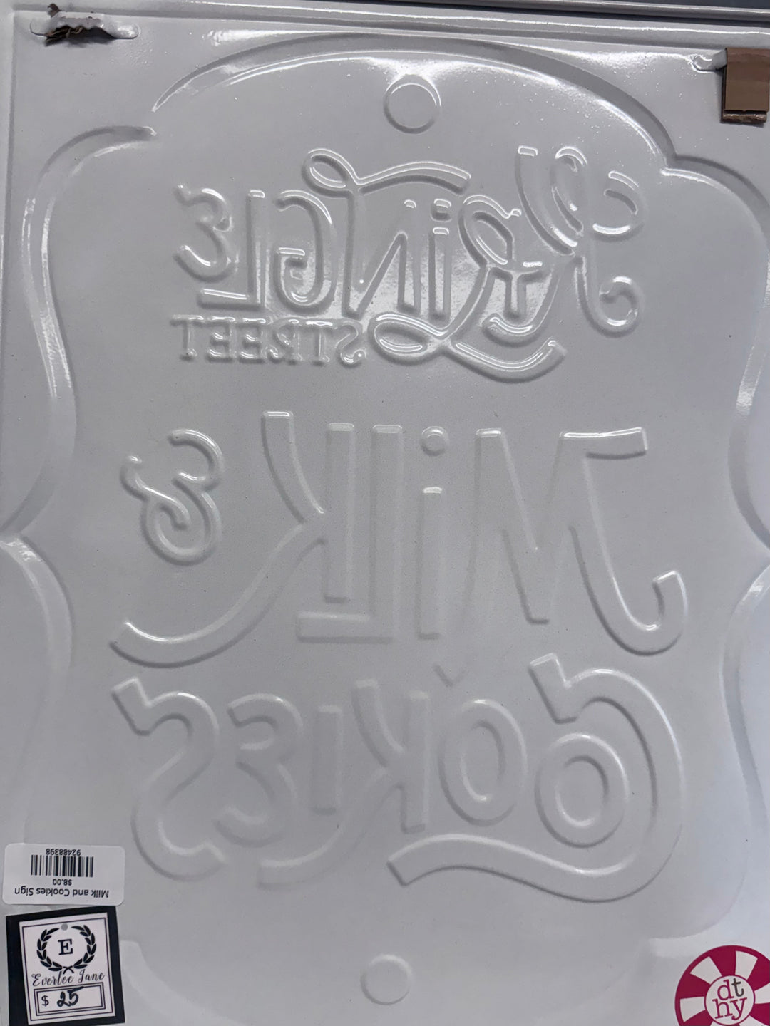 Embossed white metal Milk and Cookies sign with script lettering.