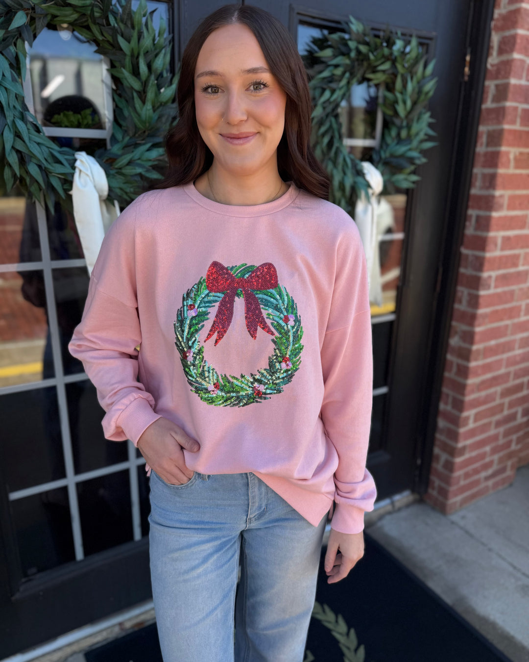 Pink Clara Wreath Sequin Sweatshirt with holiday wreath and red bow design. Available in all sizes.