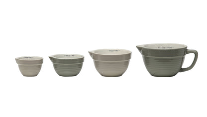 Set of four stackable ceramic measuring cups in gray and white with markings; largest has handle and spout; sizes: 1, 1/2, 1/3, 1/4 cup.
