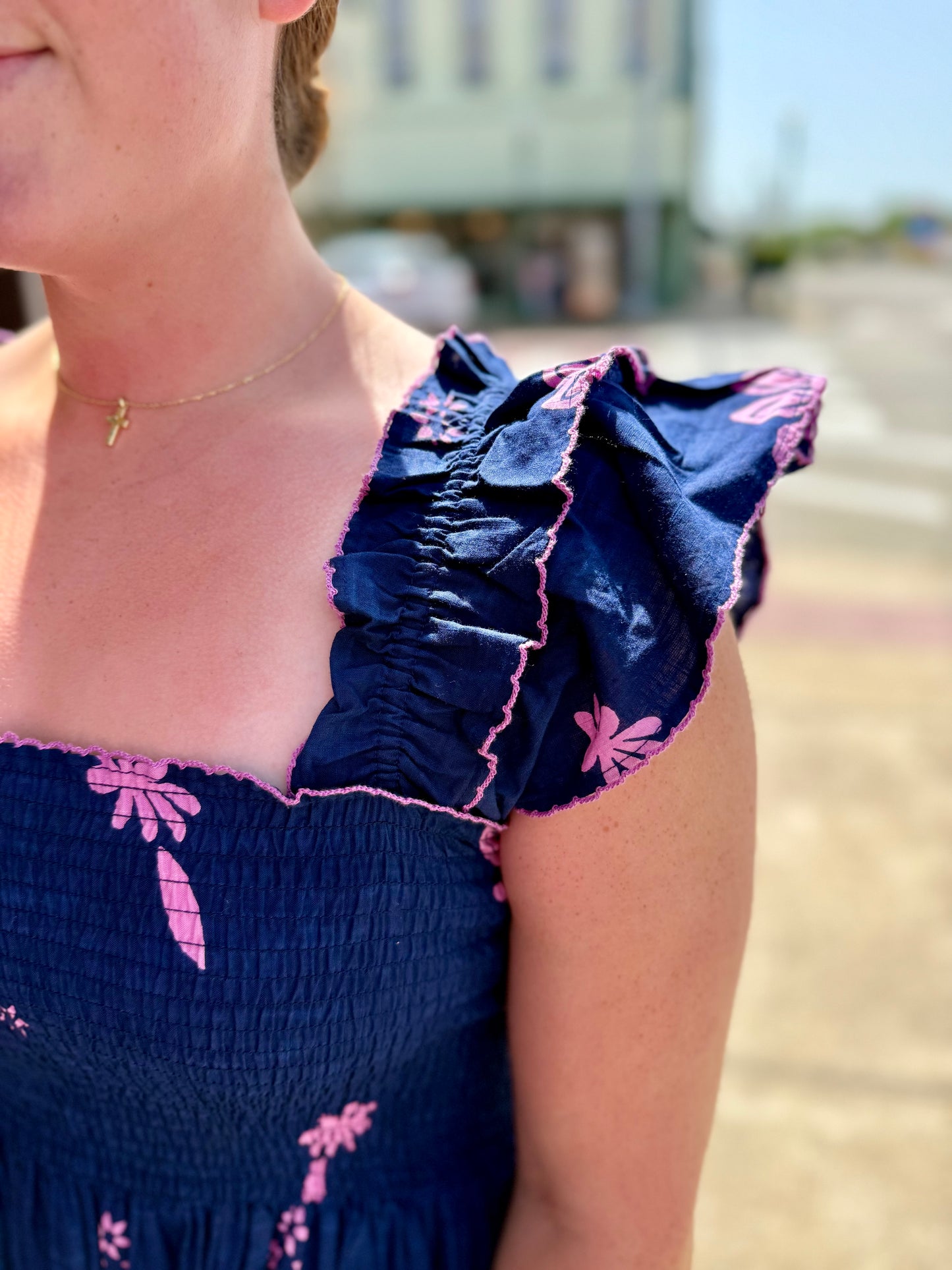 Navy Smocked Border Dress with pink florals and ruffled sleeves; available in sizes XS-XL.
