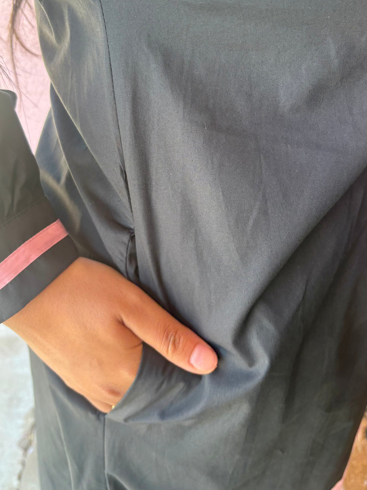 Dark garment with pink and black puff sleeves, featuring smooth fabric folds and elegant pocket detailing. Available in sizes XS-XL.