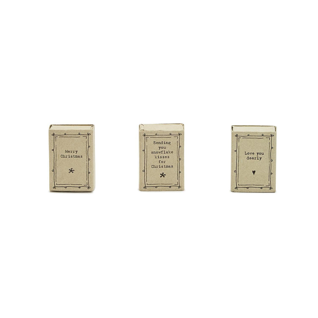 Three ceramic mini matchboxes with handwritten-style labels reading “Merry Christmas,” “Sending you snowflake kisses for Christmas,” and “Love you deerly.”.