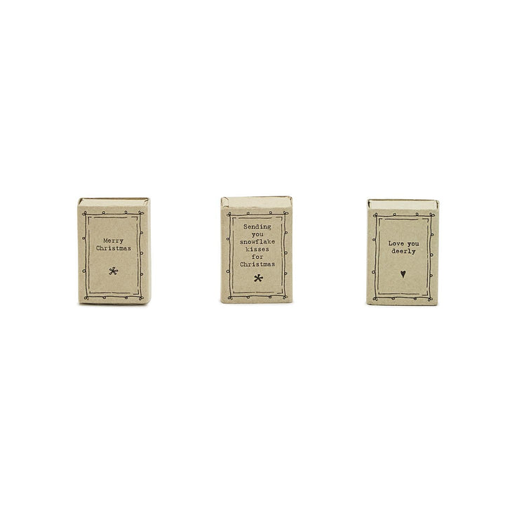 Three ceramic mini matchboxes with handwritten-style labels reading “Merry Christmas,” “Sending you snowflake kisses for Christmas,” and “Love you deerly.”.