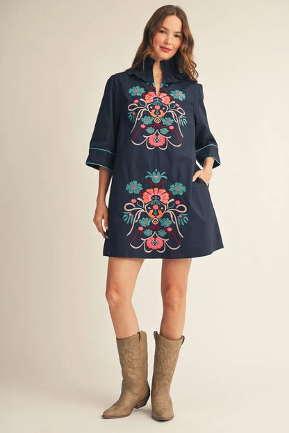 Cecilia Floral Embroidered Dress: navy mini dress with colorful embroidery and ruffled neckline; available in sizes XS–XL.