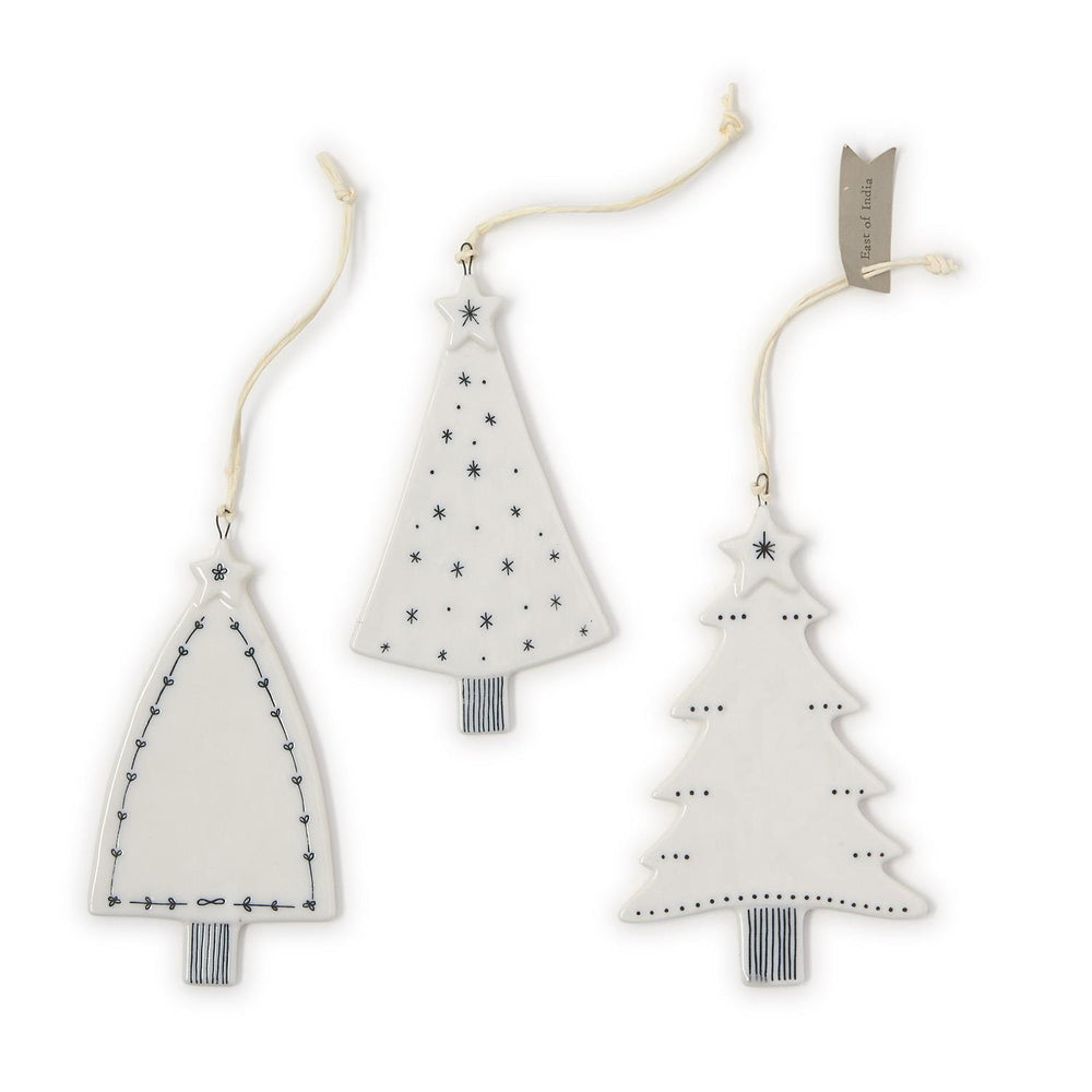 Three white ceramic Christmas tree ornaments with black line work and star motifs.