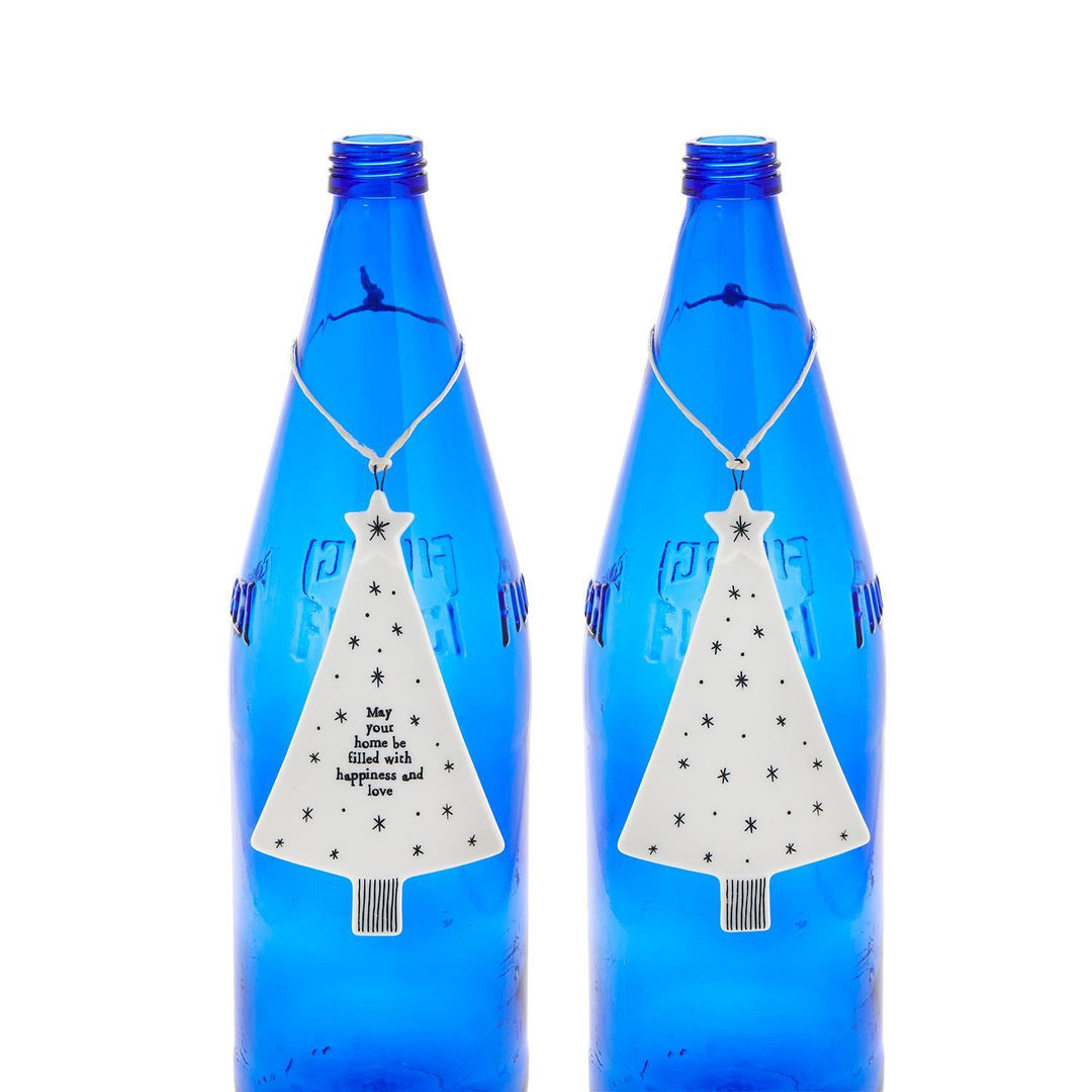 Two white, tree-shaped Christmas ornaments decorated with black stars, one featuring the text “May your home be filled with happiness and love.”.