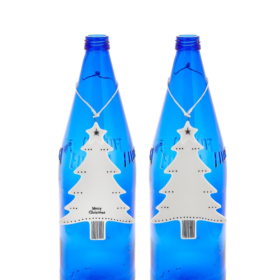 Two white ceramic Christmas tree hanging ornaments with a star topper and “Merry Christmas” base.