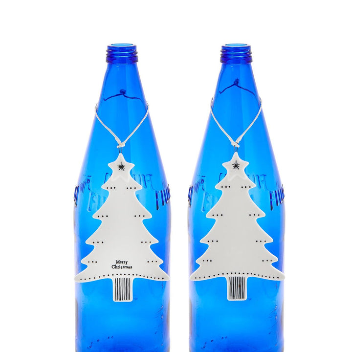 Two white ceramic Christmas tree hanging ornaments with a star topper and “Merry Christmas” base.