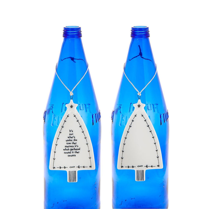 Two tree-shaped Christmas ornaments; one is blank, one features the text: “It’s not what’s under the tree that matters it’s who’s gathered round it that counts.”.
