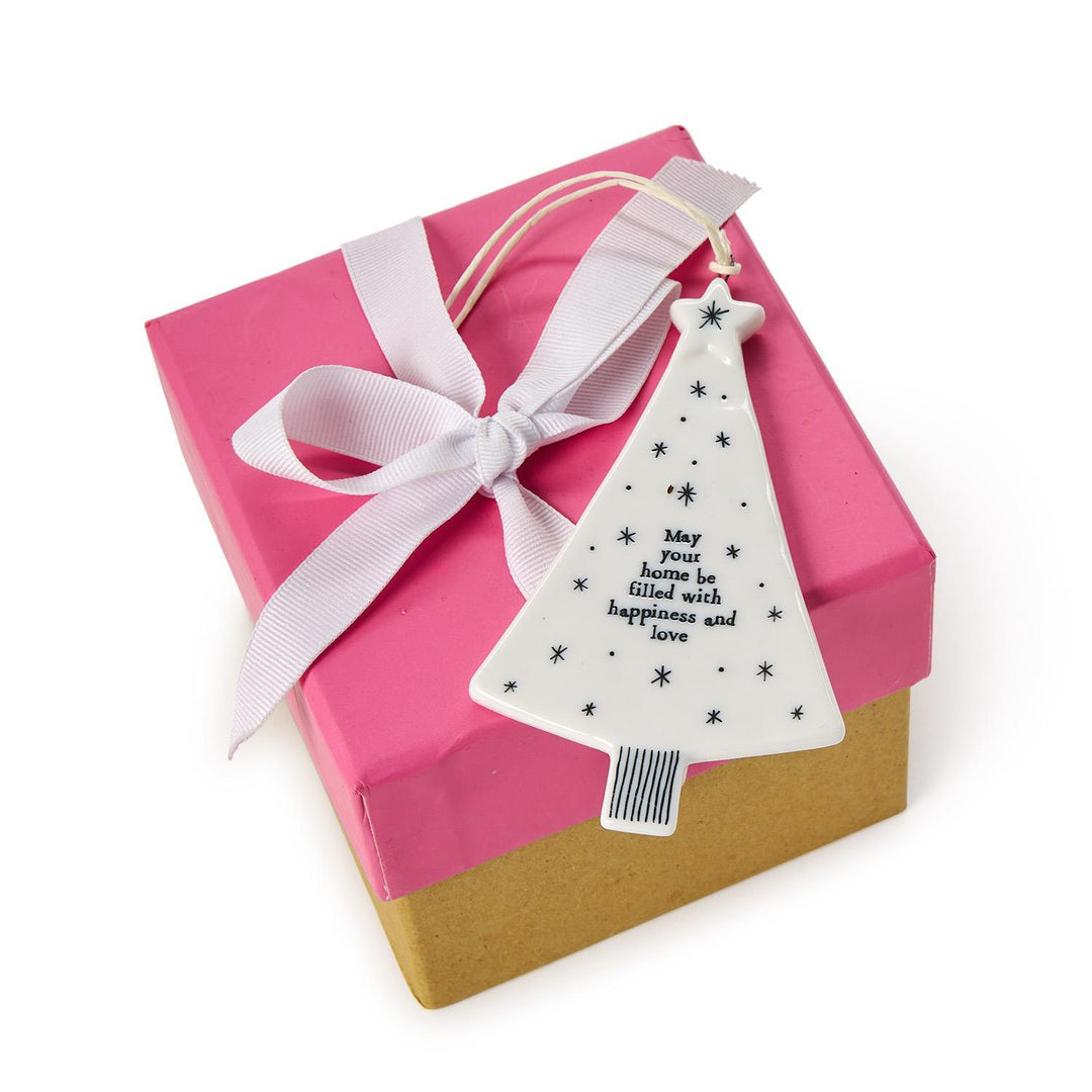 White ceramic Christmas tree hanging ornament with a string loop, star accents, and the text “May your home be filled with happiness and love.”.