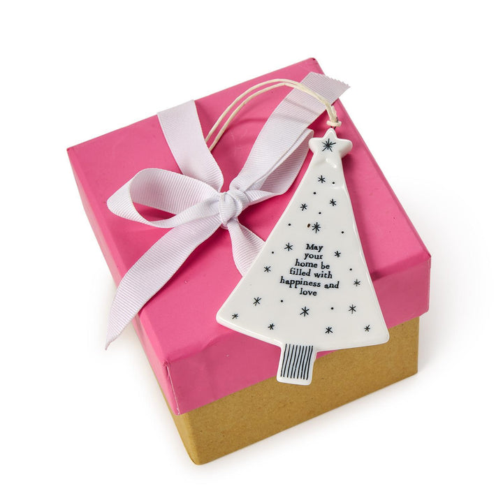 White ceramic Christmas tree hanging ornament with a string loop, star accents, and the text “May your home be filled with happiness and love.”.