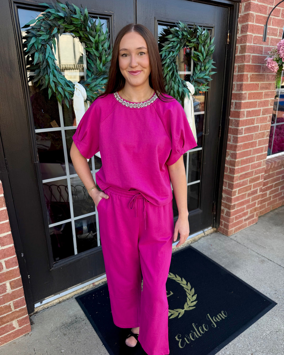 Fuchsia short-sleeve top with rhinestone-embellished neckline and matching fuchsia barrel knit pant with drawstring waist and side pockets.