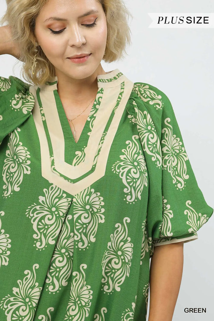 Green abstract print midi dress with beige floral patterns and a beige-trimmed neckline, made from breathable fabric in a flowy, plus-size silhouette. Available in plus sizes.
