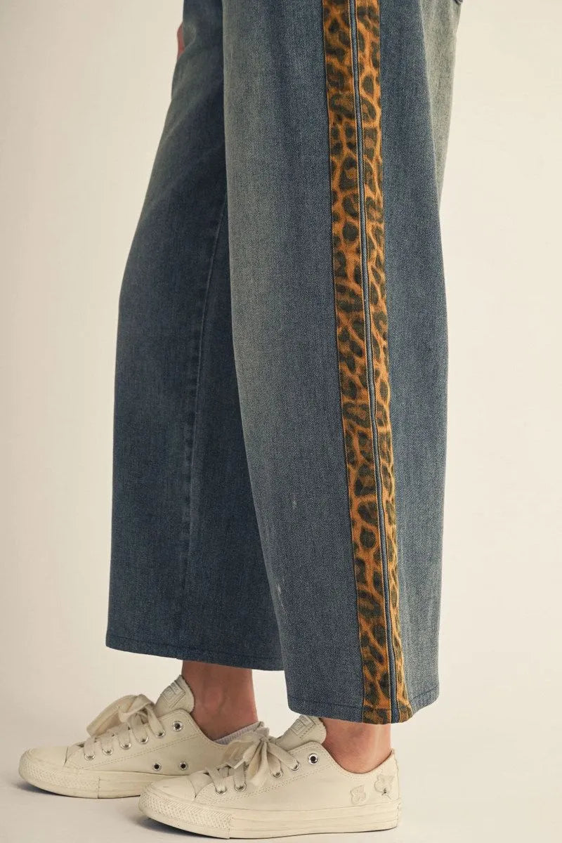 Cheetah Contrast Jeans: wide-leg, washed denim with drawstring waist and vertical cheetah-print side detailing. Available in sizes XS–XL.