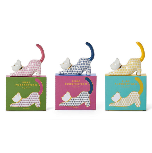 Set of three Pure Purfection Ring Holders with minimalistic stretching ceramic cats in pink, blue, and yellow patterns. Each ring holder sits on a matching "PURE PURRFECTON" box with a playful cat illustration. Available in one size per set.