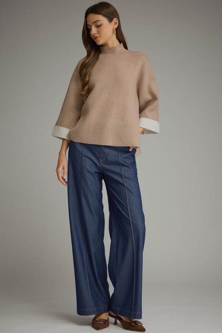 Contrast mock neck sweater in tan with white cuffs and three-quarter sleeves. Available in sizes XS-XL.