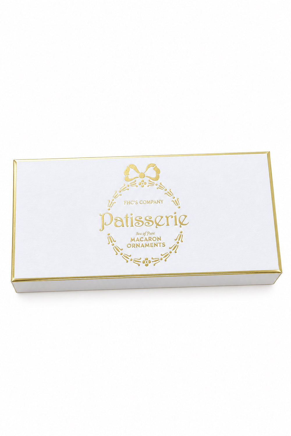 Light pink rectangular gift box containing four macaron ornaments with gold foil text reading “Patisserie set of four MACARON ORNAMENTS.”