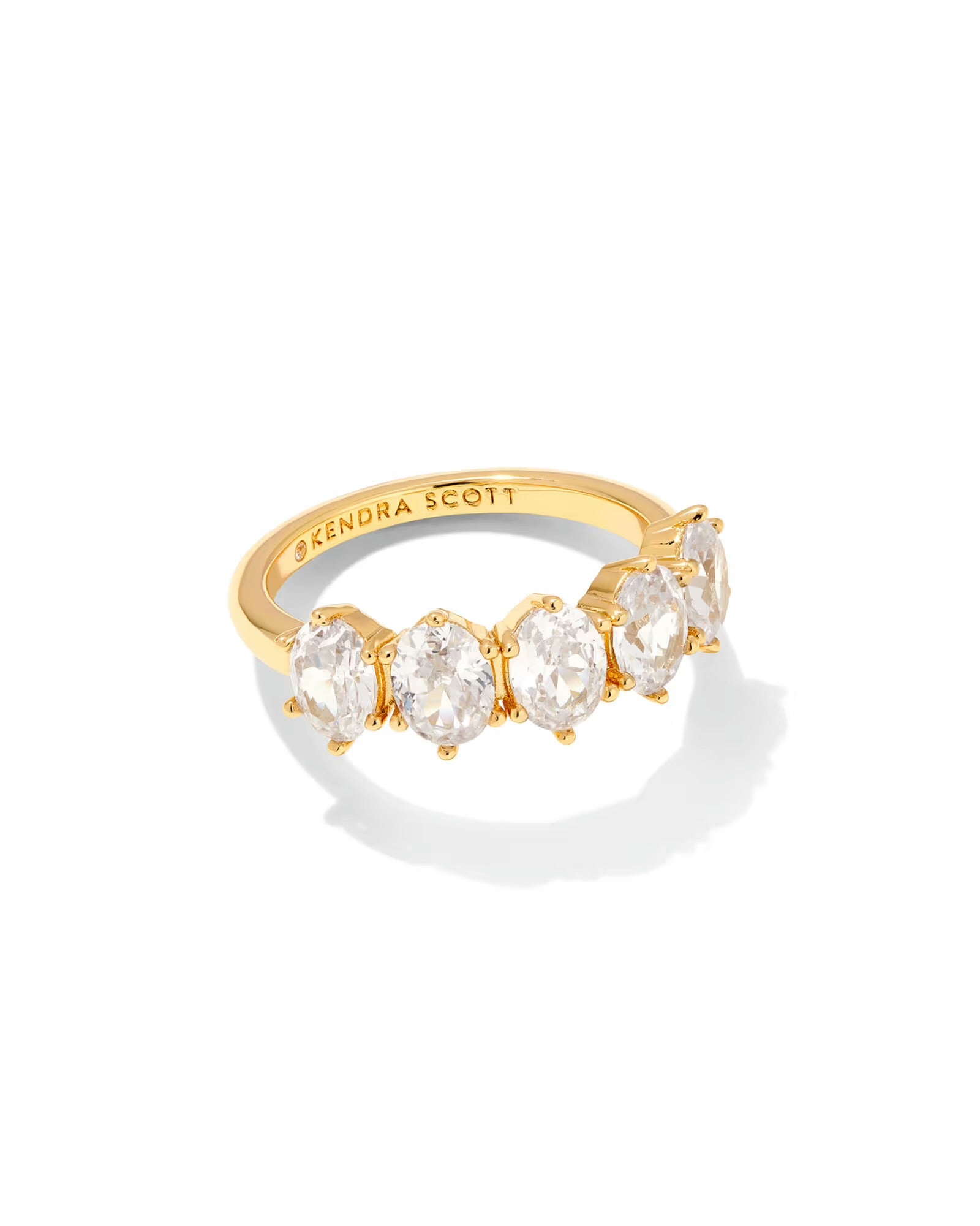 The Cailin Crystal Gold Band has five oval white crystals in gold with "Kendra Scott" inside. Available in sizes 5–9.