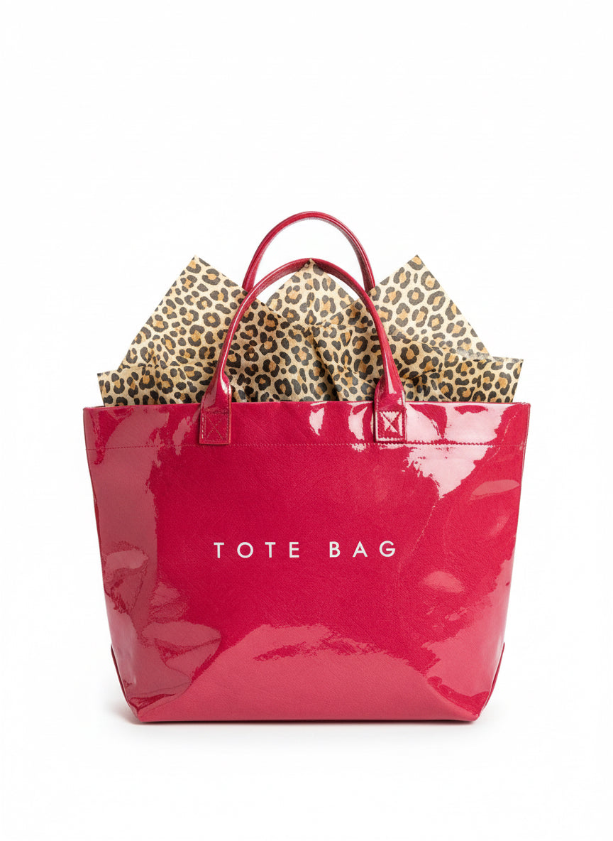 Shiny red waterproof tote with bold "TOTE BAG" print and leopard-print tissue paper. Available in small, medium, large.