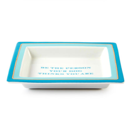 Rectangular white porcelain tray with a blue border, gold trim, and blue lettering that reads "BE THE PERSON YOUR DOG THINKS YOU ARE." Available in one size.