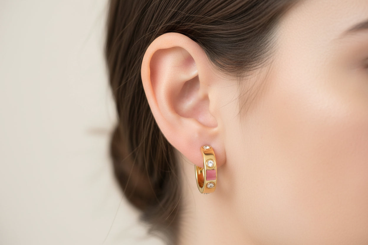 Gold hoop earrings with pink enamel and small gemstones, available in small, medium, and large sizes.