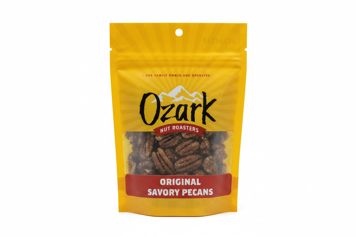 Yellow bag of Savory Pecans from Ozark Nut Roasters with a clear window showing the pecans, mountain graphics, and family owned note. Sizes available.