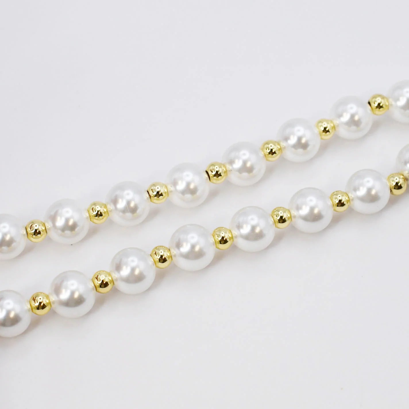 The Heart Pearl Necklace has two strands of white pearls with gold beads. Available in 16-inch and 18-inch sizes.