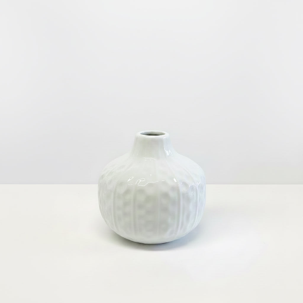 Small round white ceramic vase with hand-carved details and narrow opening; available sizes: small.
