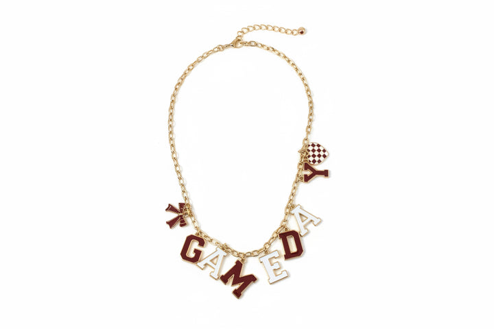 Gold chain necklace with red and white football-themed charms spelling “GAME DAY,” a small red-and-white checkered bead, and an attached Nestiere tag. Available in multiple sizes.