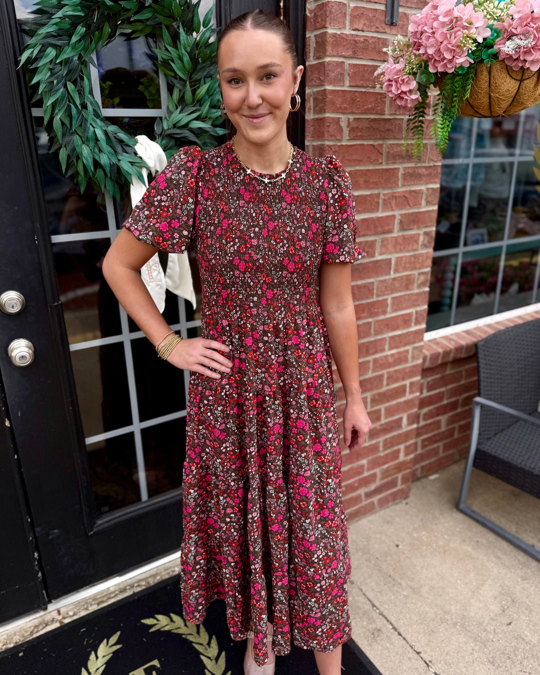 Lucille Granada Glen Cocoa Dress with pink, red, and green floral patterns and a smocked bodice. Available in sizes XS-XL.