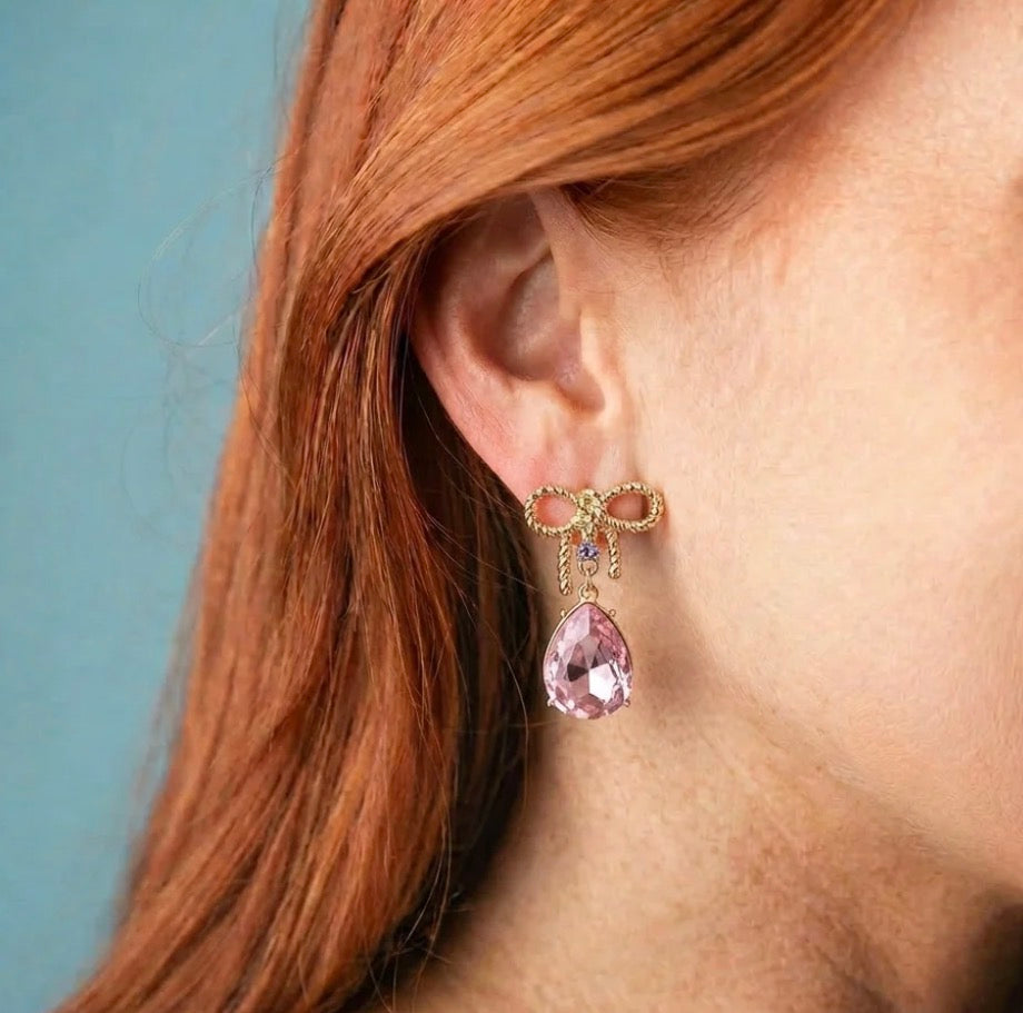 Gold Bow Teardrop Earrings with gold bows, small gems, and large pink teardrop-shaped gemstone; available in small, medium, and large sizes.